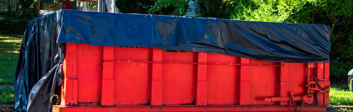 A red dumpster with a black tarp on top.