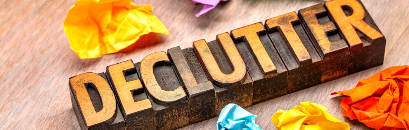Wooden blocks with the word declutter surrounded by crumpled colored paper.