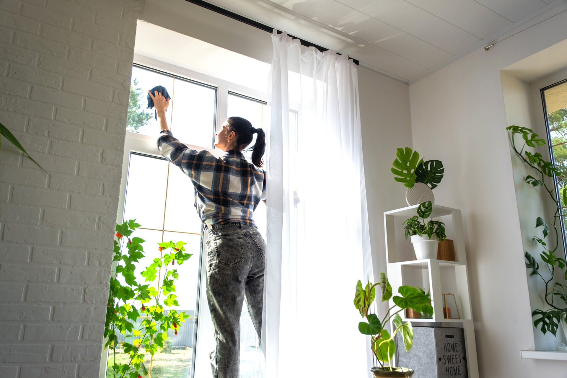 A woman in a plaid shirt cleaning a window