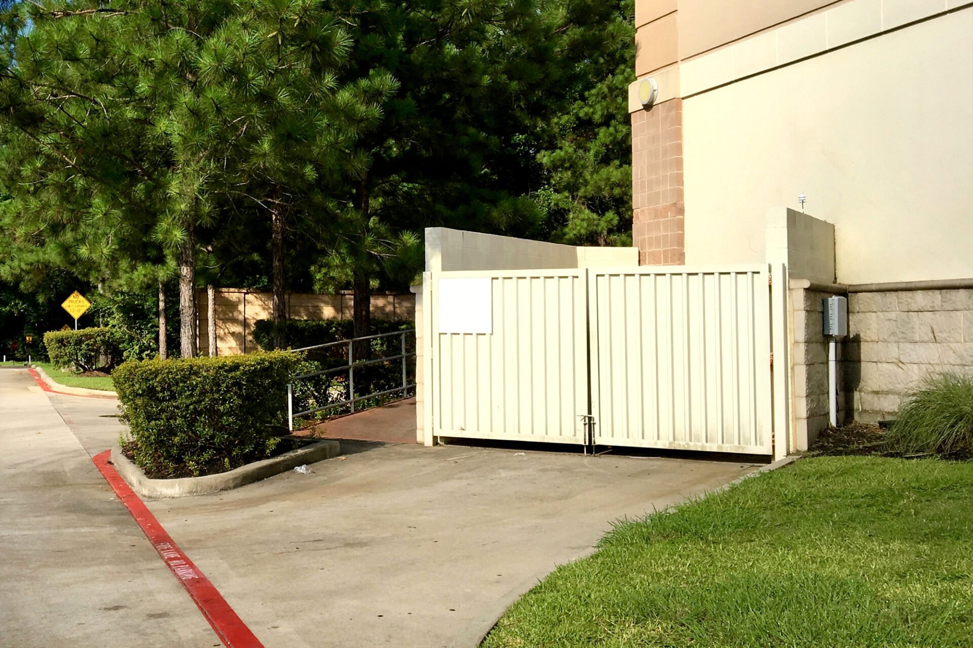 A beige gate beside a building. The gate is closed.