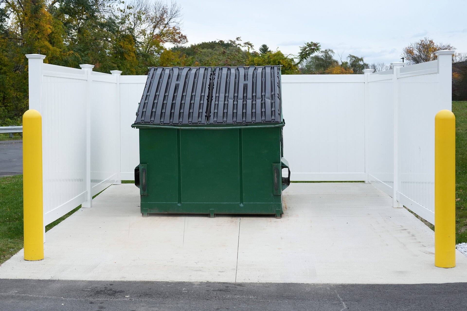 Large green metal dumpster with black lid